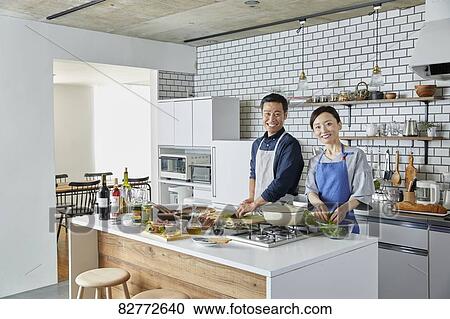 Stock Image - Japanese mature couple in the kitchen. Fotosearch