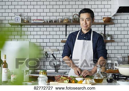 Stock Photo - Japanese mature man in the kitchen. Fotosearch