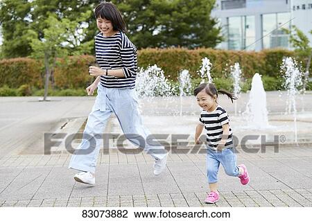 Stock Image - Japanese mother and daughter at a city park. Fotosearch