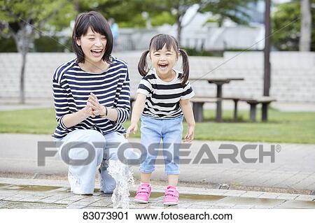 Stock Image - Japanese mother and daughter at a city park. Fotosearch