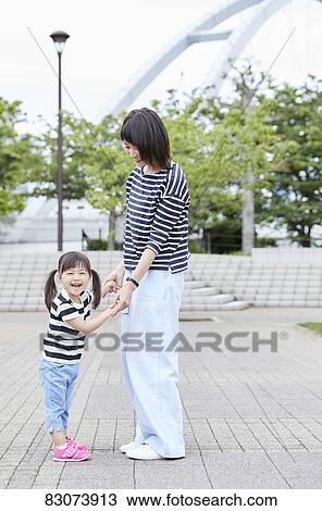 Stock Image - Japanese mother and daughter at a city park. Fotosearch