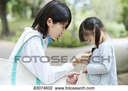 Stock Image - Japanese mother and daughter at a city park. Fotosearch