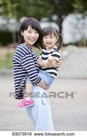 Stock Photo - Japanese mother and daughter at a city park. Fotosearch