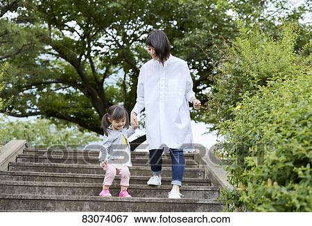 Stock Photo - Japanese mother and daughter at a city park. Fotosearch