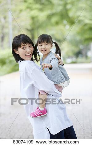 Stock Photo - Japanese mother and daughter at a city park. Fotosearch