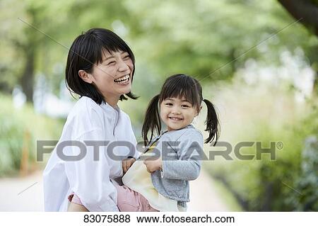 Stock Photo - Japanese mother and daughter at a city park. Fotosearch