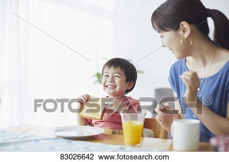 Stock Image - Japanese mother and kid having breakfast. Fotosearch