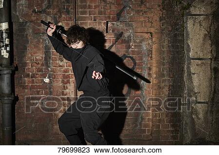 Stock Image - Japanese ninja at night downtown Tokyo. Fotosearch