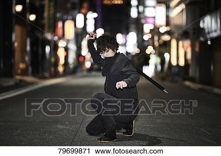 Stock Image - Japanese ninja at night downtown Tokyo. Fotosearch