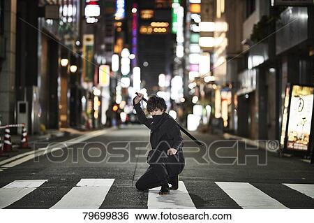 Stock Photograph - Japanese ninja at night downtown Tokyo. Fotosearch
