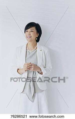 Stock Image - Japanese senior businesswoman against white wall. Fotosearch