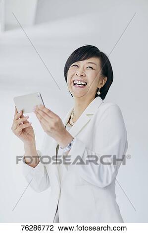 Stock Image - Japanese senior businesswoman against white wall. Fotosearch