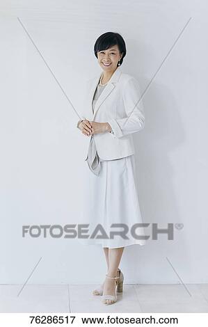 Stock Photo - Japanese senior businesswoman against white wall. Fotosearch