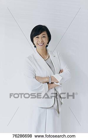 Stock Photo - Japanese senior businesswoman against white wall. Fotosearch