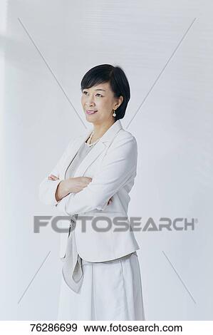 Stock Photo - Japanese senior businesswoman against white wall. Fotosearch