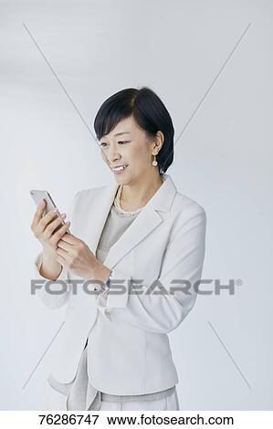 Stock Photo - Japanese senior businesswoman against white wall. Fotosearch