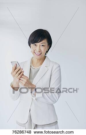 Japanese senior businesswoman against white wall View Large Photo Image Stock Photo - Japanese senior businesswoman against white wall. Fotosearch