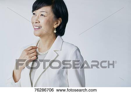 Stock Photograph - Japanese senior businesswoman against white wall. Fotosearch