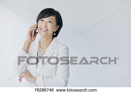 Stock Photograph - Japanese senior businesswoman against white wall. Fotosearch