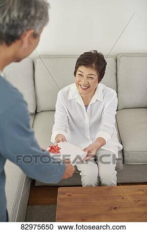 Stock Image - Japanese senior couple exchanging gifts. Fotosearch