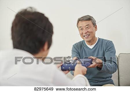 Stock Photo - Japanese senior couple exchanging gifts. Fotosearch