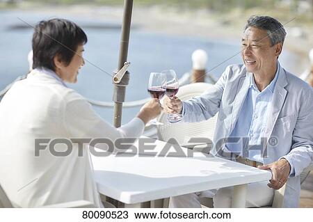 Stock Image - Japanese senior couple having a drink by the sea. Fotosearch