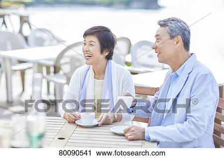Stock Image - Japanese senior couple having a drink by the sea. Fotosearch