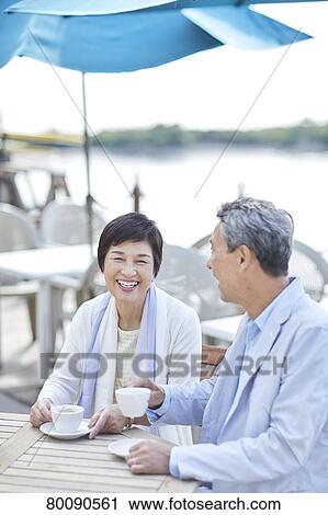 Stock Image - Japanese senior couple having a drink by the sea. Fotosearch