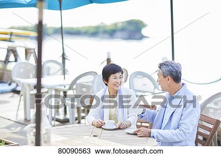 Stock Image - Japanese senior couple having a drink by the sea. Fotosearch