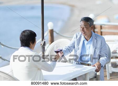 Stock Image - Japanese senior couple having a drink by the sea. Fotosearch