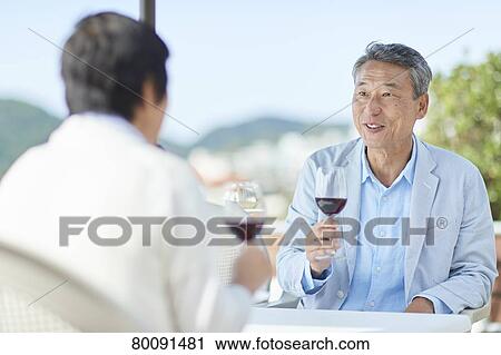 Stock Image - Japanese senior couple having a drink by the sea. Fotosearch