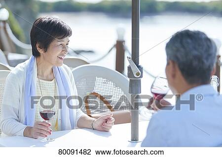 Stock Image - Japanese senior couple having a drink by the sea. Fotosearch