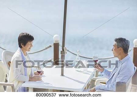 Stock Photo - Japanese senior couple having a drink by the sea. Fotosearch