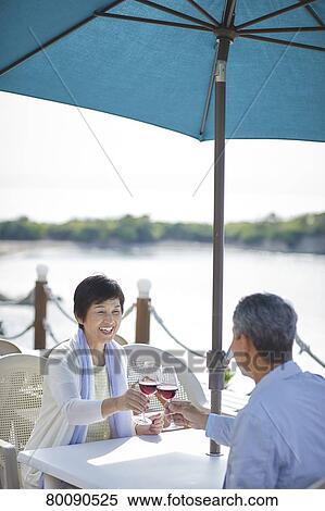 Stock Photography - Japanese senior couple having a drink by the sea. Fotosearch
