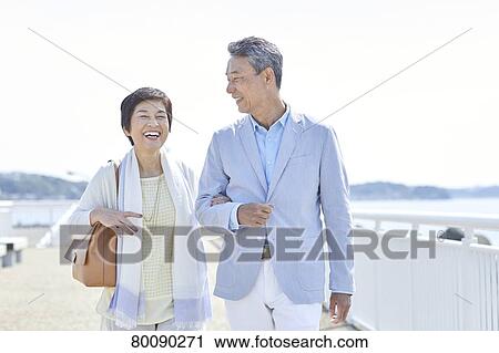 Stock Image - Japanese senior couple having fun by the sea. Fotosearch