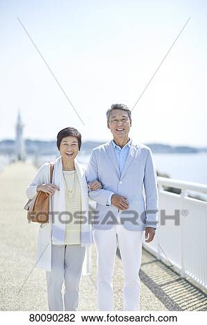 Stock Image - Japanese senior couple having fun by the sea. Fotosearch