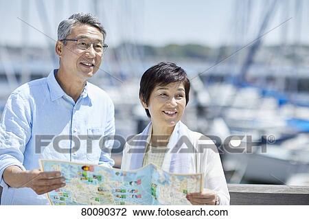 Stock Image - Japanese senior couple having fun by the sea. Fotosearch