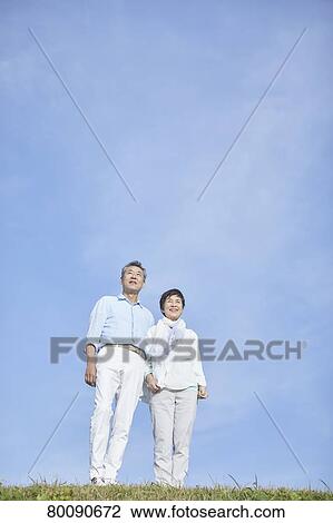 Stock Image - Japanese senior couple having fun by the sea. Fotosearch