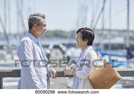 Stock Photo - Japanese senior couple having fun by the sea. Fotosearch