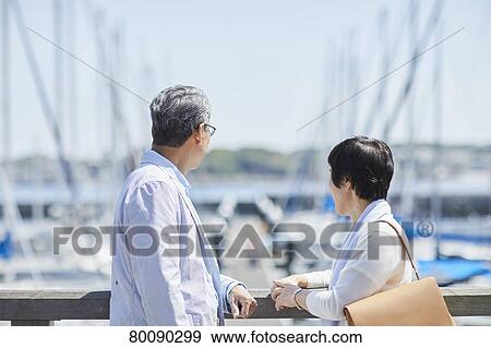 Stock Photo - Japanese senior couple having fun by the sea. Fotosearch