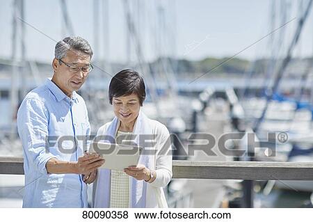 Stock Photo - Japanese senior couple having fun by the sea. Fotosearch