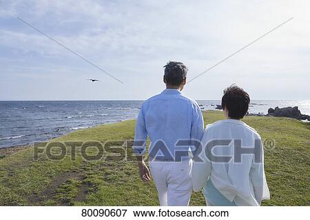Stock Photo - Japanese senior couple having fun by the sea. Fotosearch