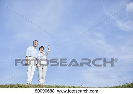 Stock Photo - Japanese senior couple having fun by the sea. Fotosearch