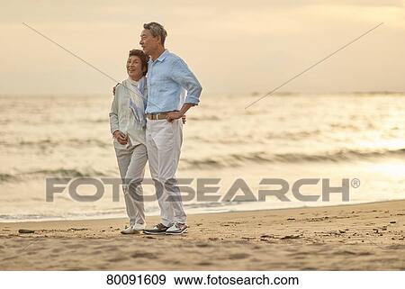 Stock Photo - Japanese senior couple having fun by the sea. Fotosearch
