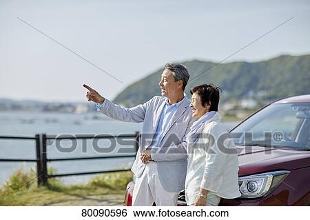 Stock Photograph - Japanese senior couple having fun by the sea. Fotosearch