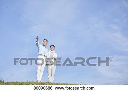 Stock Photograph - Japanese senior couple having fun by the sea. Fotosearch