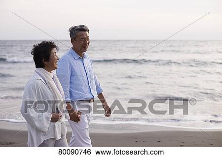 Stock Photograph - Japanese senior couple having fun by the sea. Fotosearch