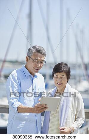 Stock Photography - Japanese senior couple having fun by the sea. Fotosearch