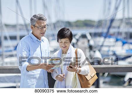 Stock Photography - Japanese senior couple having fun by the sea. Fotosearch