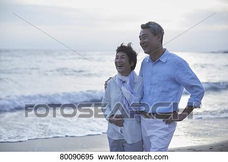 Stock Photography - Japanese senior couple having fun by the sea. Fotosearch